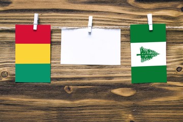 Hanging flags of Guinea and Norfolk Island attached to rope with clothes pins with copy space on...