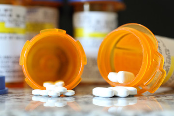 Precription bottles of pain pills on a granite countertop. 