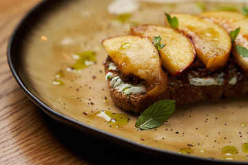 Traditional italian bruschetta with duck fillet, cream cheese and peach, close-up