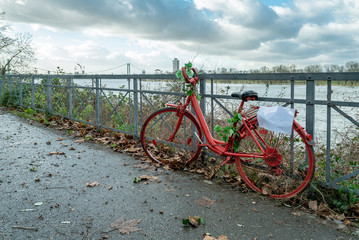 Altes rotes Fahrrad an Geländer mit Fluss im Hintergrund