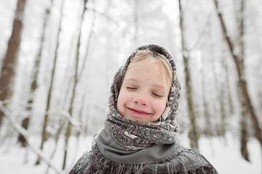 Portrait of happy little girl wearing headscarf in winter forest