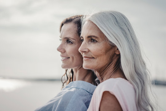 Side view of smiling mother and daughter standing outdoors