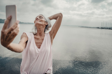 Senior woman taking smartphone selfies at the sea