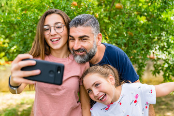 Happy father with two daughters taking selfie in garden