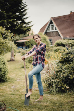 Proud home owner standing in her garden with a spade