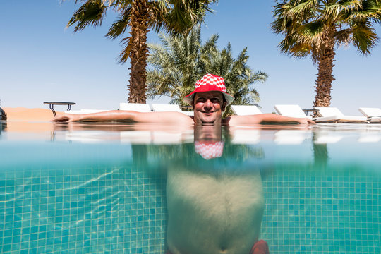 Overweight man with hat bathing in pool