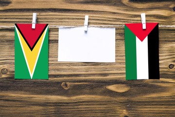 Hanging flags of Guyana and Palestine attached to rope with clothes pins with copy space on white...