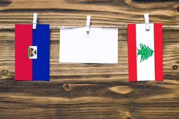 Hanging flags of Haiti and Lebanon attached to rope with clothes pins with copy space on white note...