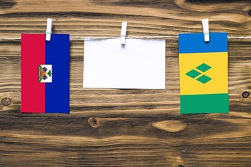 Hanging flags of Haiti and Saint Vincent And The Grenadines attached to rope with clothes pins with...