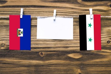 Hanging flags of Haiti and Syria attached to rope with clothes pins with copy space on white note...