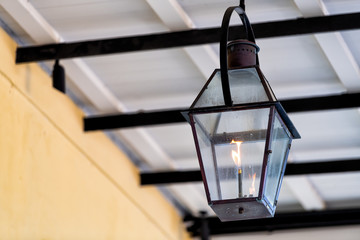 Closeup of one gas lamp lanterns during day hanging on covered sidewalk street building as...