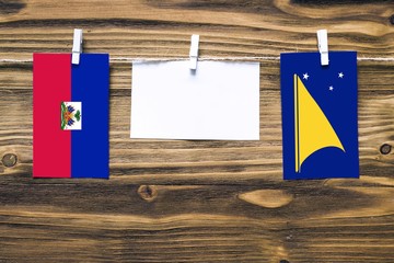 Hanging flags of Haiti and Tokelau attached to rope with clothes pins with copy space on white note...