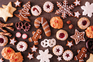 Variety of Christmas cookies and sweets. Top view over a dark stone background. Holiday baking concept. - obrazy, fototapety, plakaty