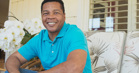 Portrait of attractive Black man smiling and sitting on porch looking at camera