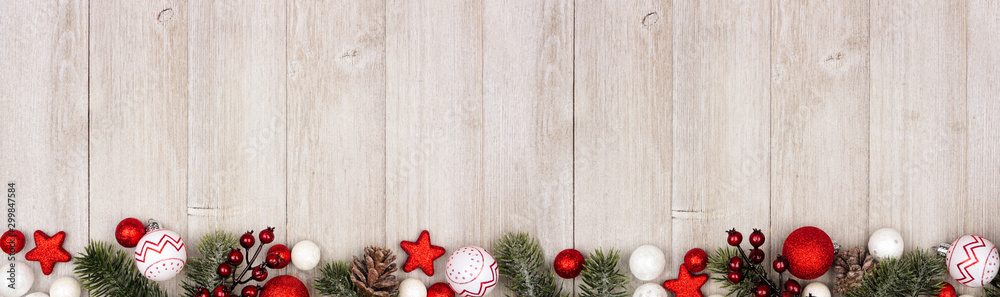 Poster christmas long border banner with red and white ornaments and branches. top view on a gray wood back
