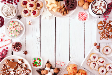 Christmas sweets and cookie frame. Top view table scene over a white wood background with copy...