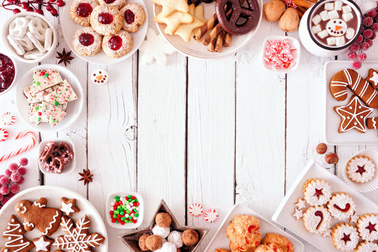 Christmas sweets and cookie frame. Top view table scene over a white wood background with copy space. Holiday baking concept.