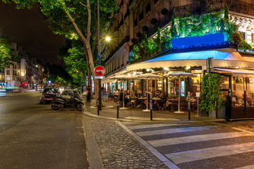 Boulevard San-German with tables of cafe in Paris at night, France