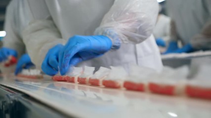 Packed crab sticks are getting removed from the belt by factory workers