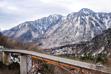 Takayama, Japan aerial high angle view of bridge and car on road in early spring in Gifu Prefecture Okuhida Villages near Shinhotaka Ropeway
