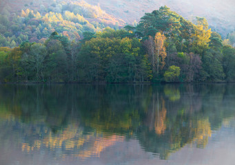 Trees change colour on the shores of Lake Grasmere in Autumn. UK