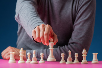 Man positioning white king chess piece in front of the other figures
