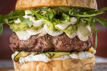 Burger, sandwich, meat, filler, rucola, sauce, bread with a cutlet, American cuisine. Traditional beautiful burger, ingredients and burger details. Food photo