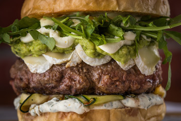 Burger, sandwich, meat, filler, rucola, sauce, bread with a cutlet, American cuisine. Traditional beautiful burger, ingredients and burger details. Food photo