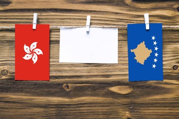 Hanging flags of Hong Kong and Kosovo attached to rope with clothes pins with copy space on white...