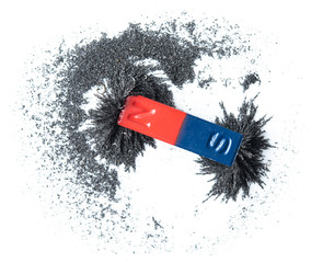 Red and blue bar magnet attracting iron powder on white background
