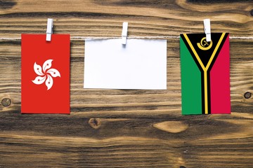 Hanging flags of Hong Kong and Vanuatu attached to rope with clothes pins with copy space on white...