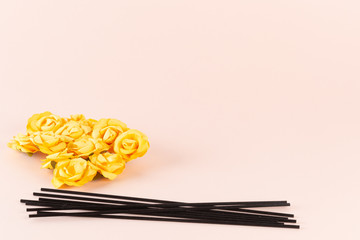 Black incense sticks with yellow flowers on pink background