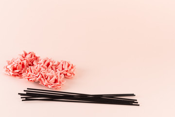 Black incense sticks with pink flowers on pink background
