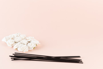 Black incense sticks with white flowers on pink background