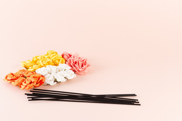 Black incense sticks with white, pink and yellow flowers on pink background