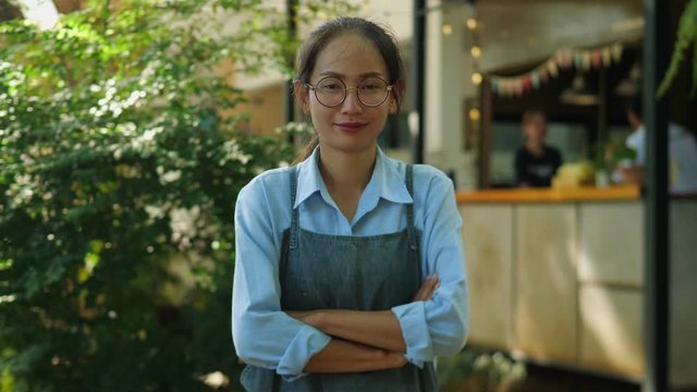 Portrait of Asian woman small business owner standing in her opening coffee shop and smiling looking at camera.