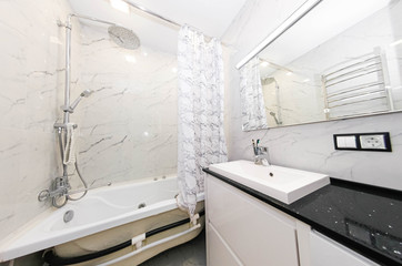 interior of a modern bathroom, heated towel rail, sink and ceramic tiles - imitation of marble.