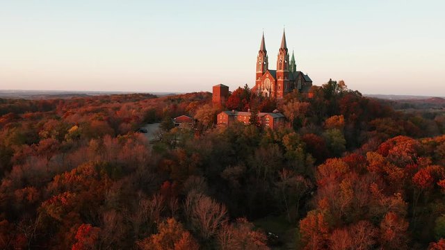 Aerial view of a church on the top of hill and autumn forest, red foliage . Fall season, autumn colors. Countryside, Wisconsin. Drone shots at sunset