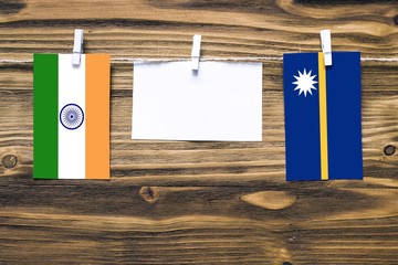 Hanging flags of India and Nauru attached to rope with clothes pins with copy space on white note paper on wooden background.Diplomatic relations between countries.