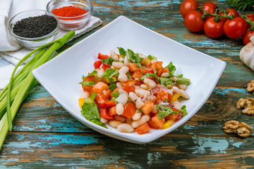 vegetable salad with white beans on wooden table