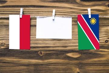 Hanging flags of Indonesia and Namibia attached to rope with clothes pins with copy space on white note paper on wooden background.Diplomatic relations between countries.