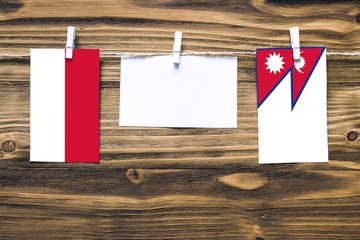 Hanging flags of Indonesia and Nepal attached to rope with clothes pins with copy space on white note paper on wooden background.Diplomatic relations between countries.