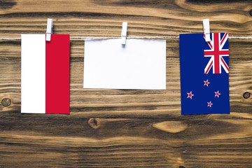 Hanging flags of Indonesia and New Zealand attached to rope with clothes pins with copy space on white note paper on wooden background.Diplomatic relations between countries.