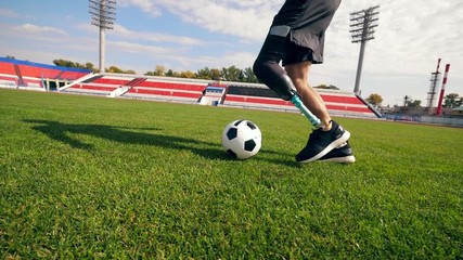 Footballer with a bionic leg is running with a ball - Powered by Adobe