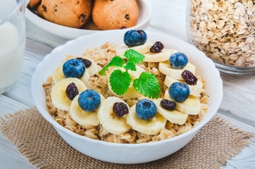 Delicious sweet healthy breakfast. Oatmeal with bananas, blueberries and cranberry.