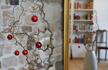 Stylish decorated christmas balls at a branch in front of old stone wall in loft