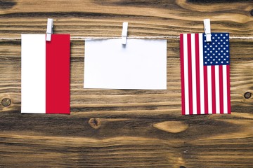 Hanging flags of Indonesia and United States attached to rope with clothes pins with copy space on white note paper on wooden background.Diplomatic relations between countries.