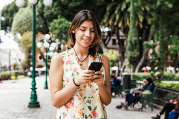hispanic woman texting with her phone, Mexican beautiful woman in Mexico