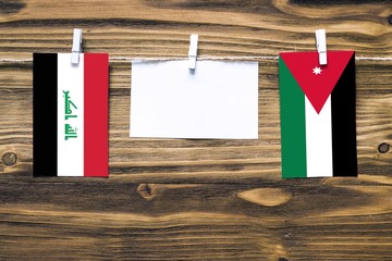 Hanging flags of Iraq and Jordan attached to rope with clothes pins with copy space on white note...