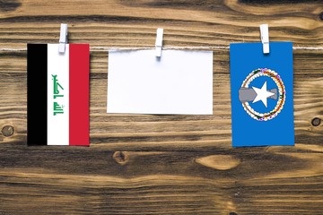 Hanging flags of Iraq and Northern Mariana Islands attached to rope with clothes pins with copy...